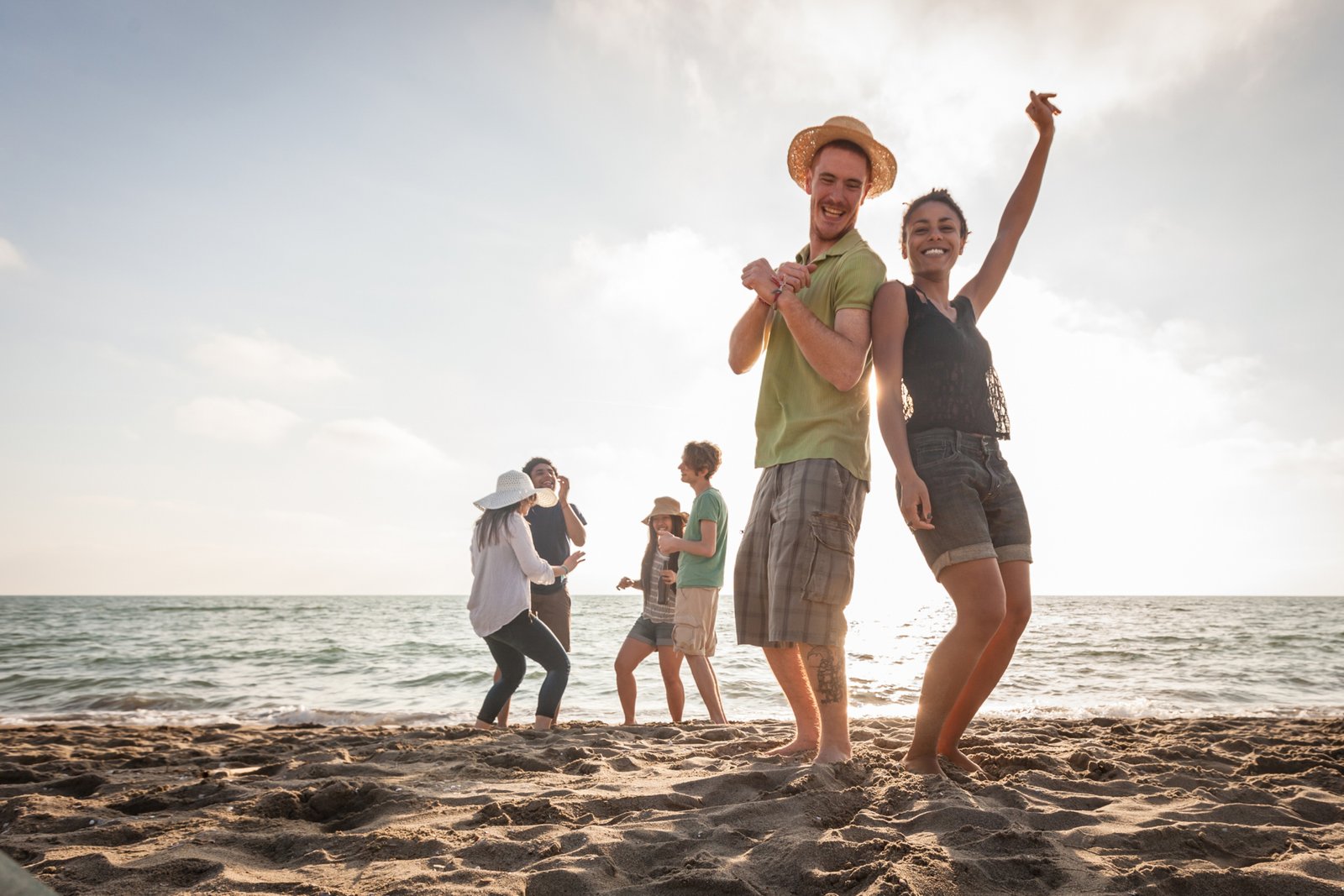 Multiracial group of friends having a party at beach. There are asiatic, black and caucasian persons. Friendship, immigration, integration concepts. Also refers to summer and party.