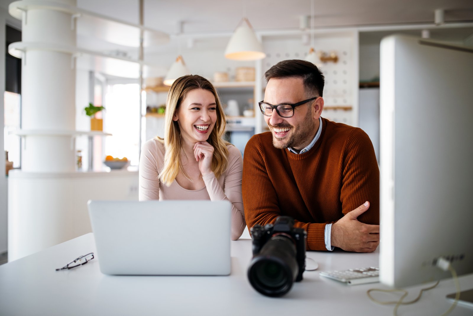 Photographer and graphic designer working in office with laptop. Creative team discussing ideas in advertising agency.