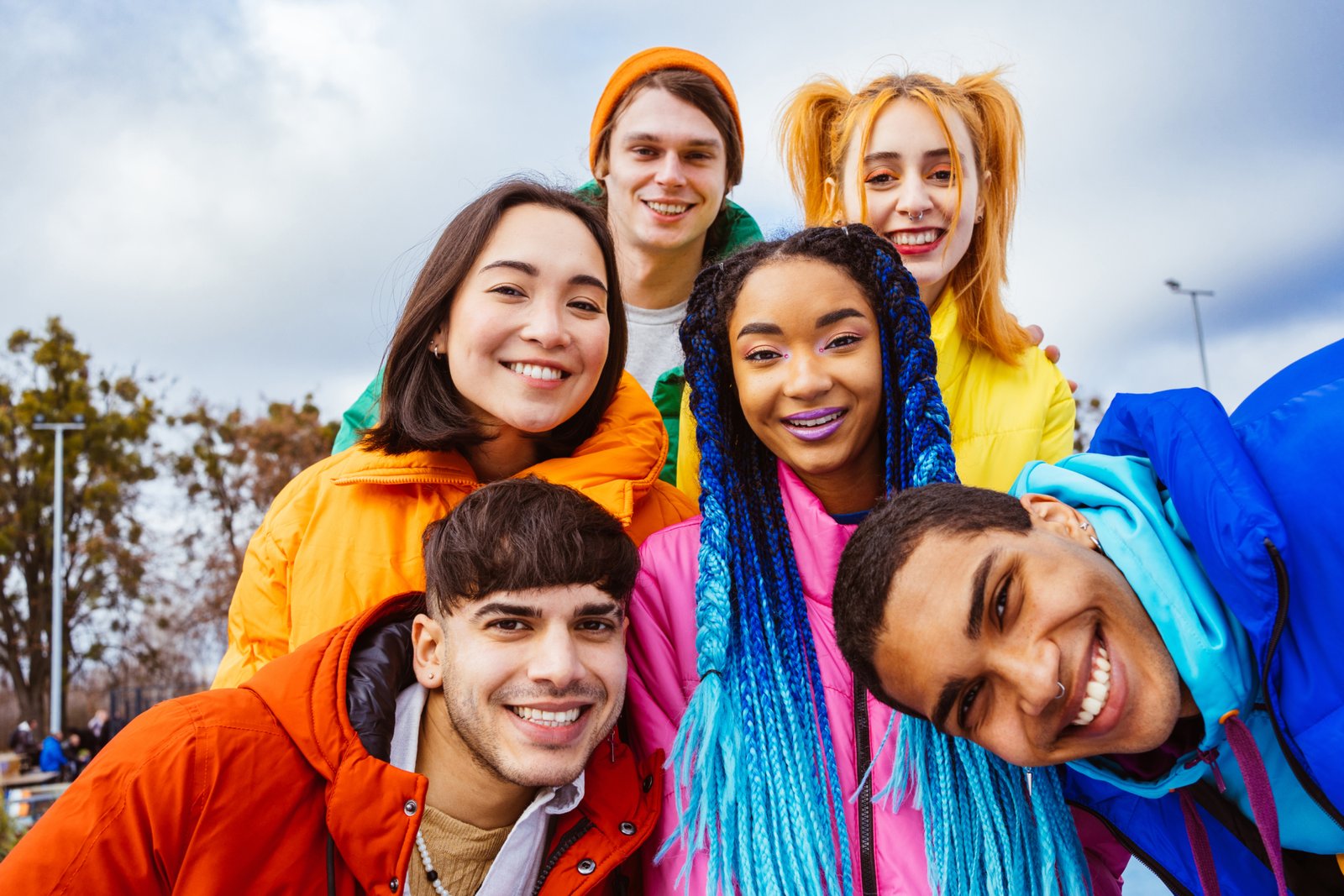 Multiracial group of young happy friends meeting outdoors in winter, wearing winter jackets and having fun - Multiethnic millennials bonding in a urban area, concepts about youth and social releationships